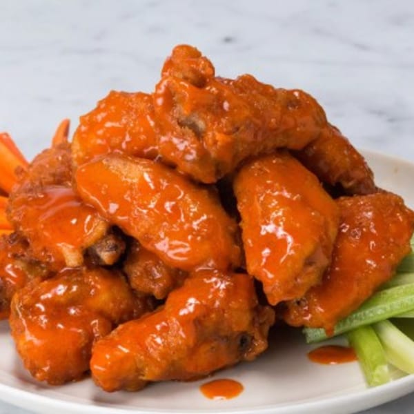 Pines Bar and Grill's buffalo wings, coated in orange sauce, with celery and carrot sticks.
